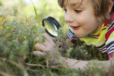 Happy little boy looking through magnifying glass